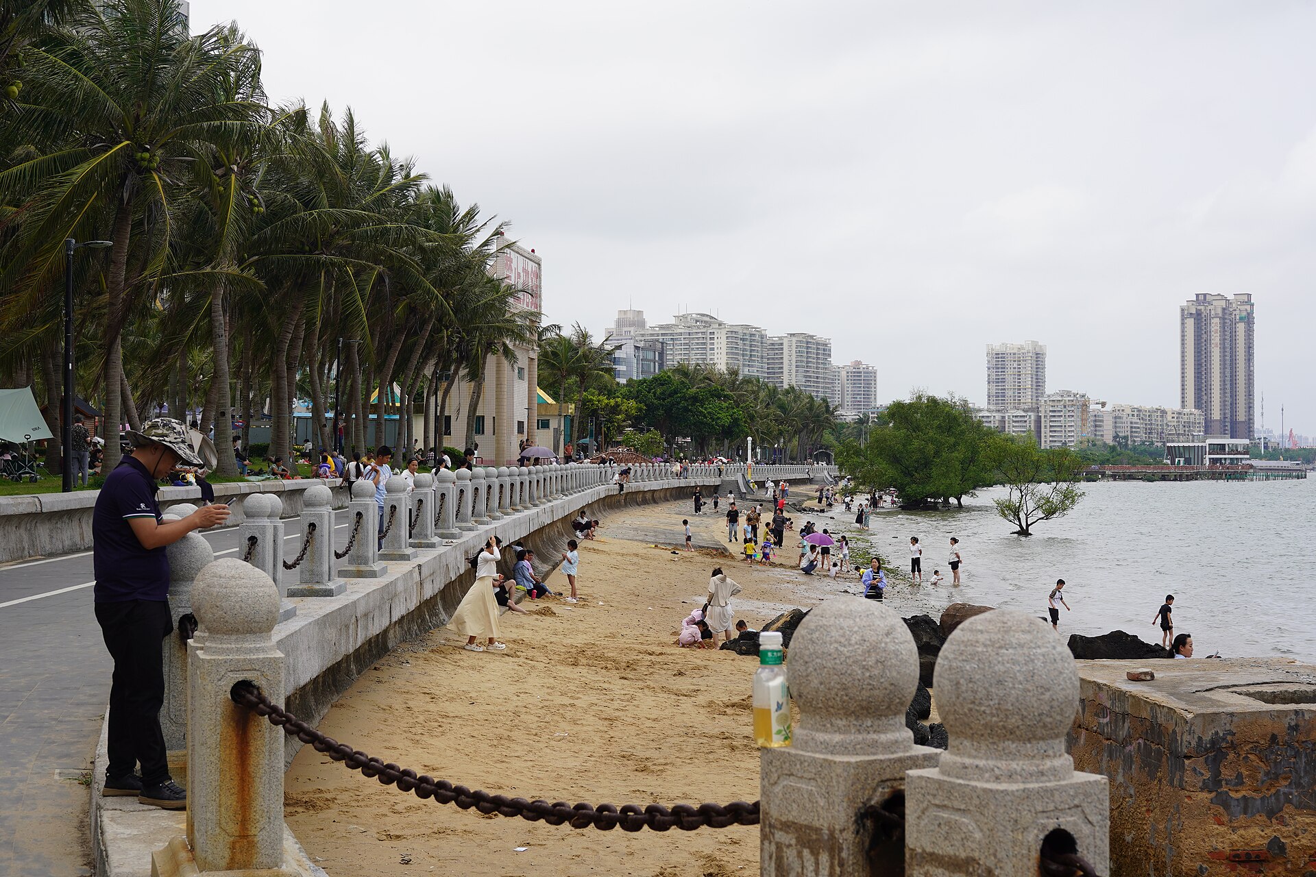 湛江海边沙滩：浅色细沙延伸至海水，浪线平缓，天空明亮