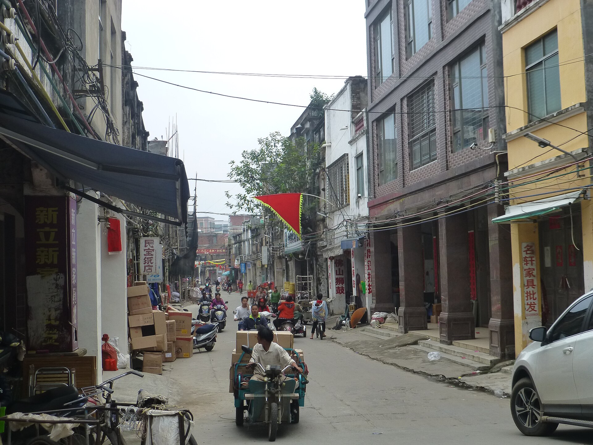 雷州古城老街：两侧为骑楼式店铺，石板路面，行人在街上走动