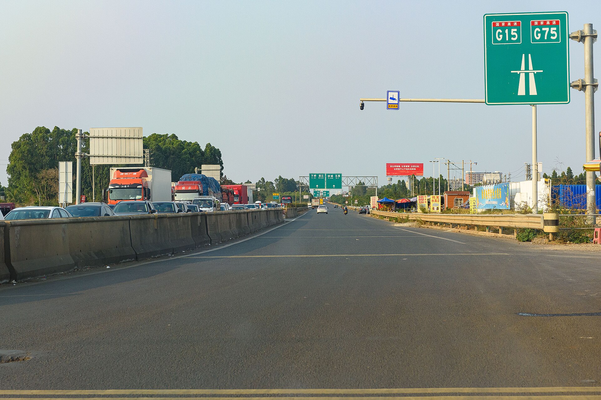 徐闻境内 G15 与 G75 高速公路起点路段：笔直的道路穿过开阔的田野，远处是低矮的丘陵